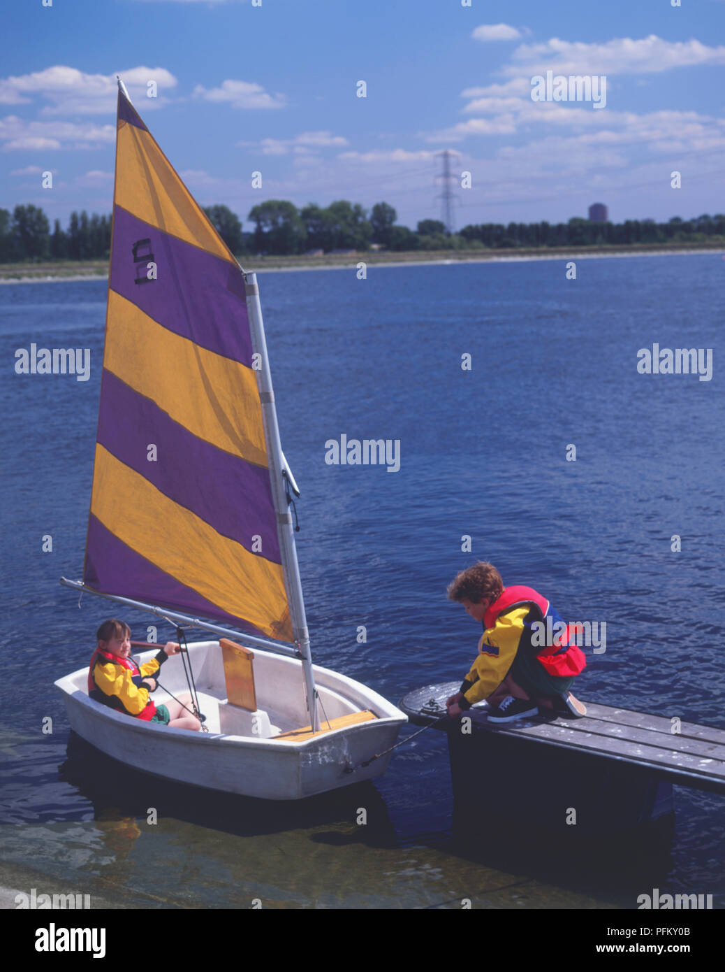 Kleines Segelboot am Ende einer Anlegestelle festgemacht, Mädchen im