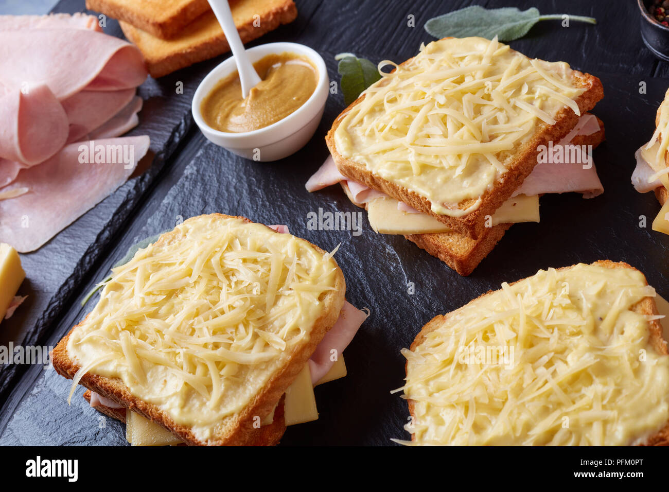French Toast Croque Monsieur vorbereitet zu backen. geröstetes Brot mit Butter Scheiben gekochten Schinken und Emmentaler Käse auf einer Steinplatte und Zutaten auf Stockfoto