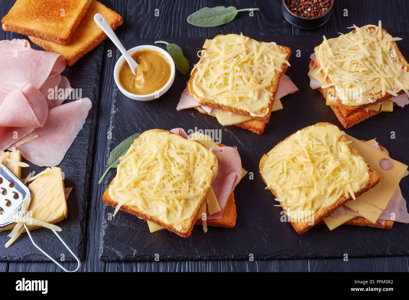 French Toast Croque Monsieur vorbereitet zu backen. geröstetes Brot mit Butter Scheiben gekochten Schinken und Emmentaler Käse auf einem Stein Fach und Zutaten auf einem Stockfoto