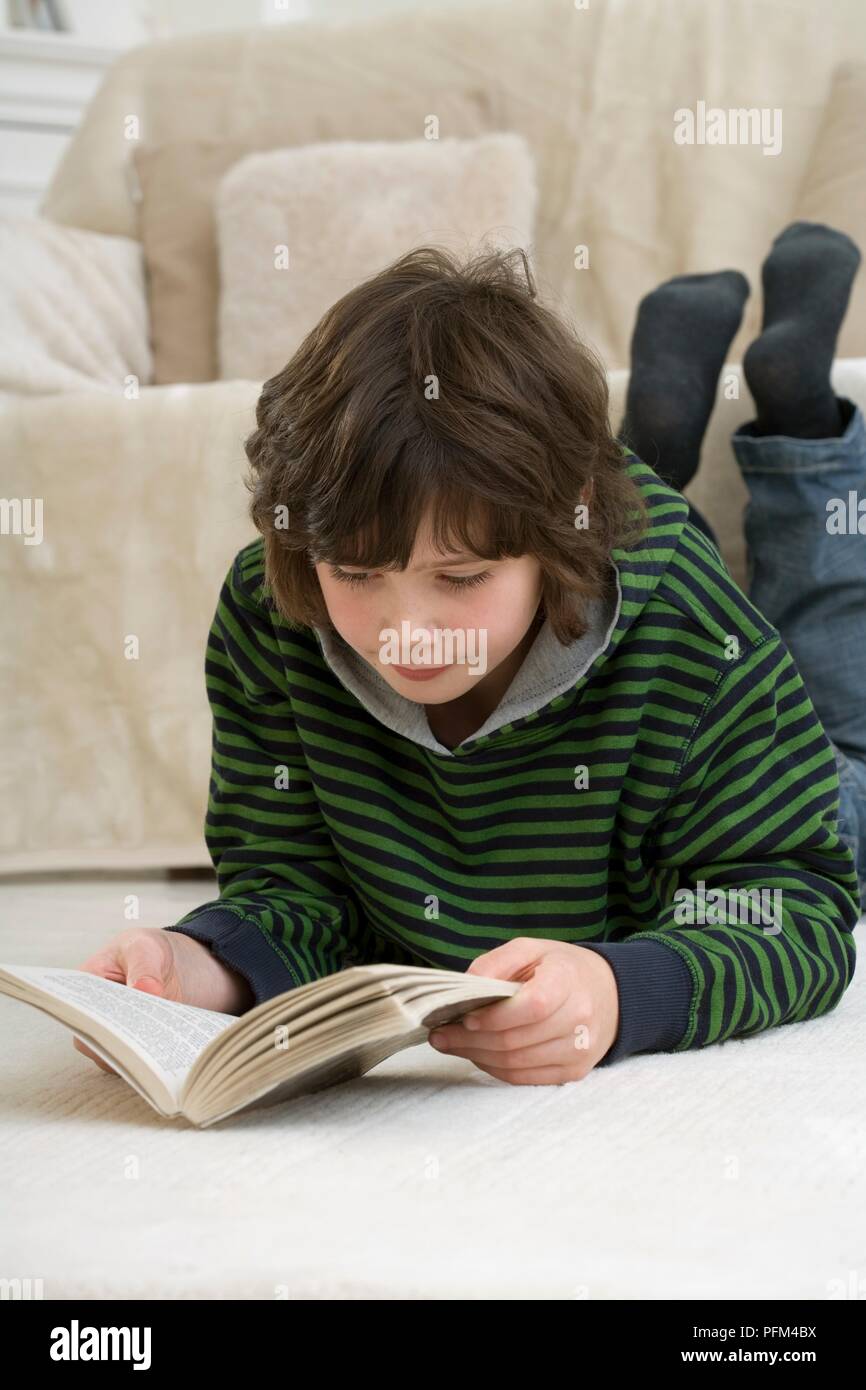 Junge liegend auf Wohnzimmer, ein Buch zu lesen Stockfoto