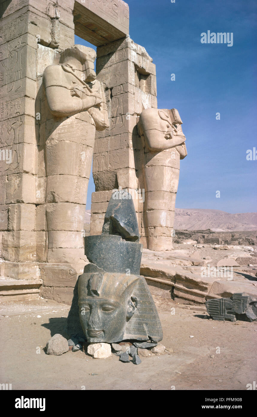 Ägypten, osirid Statuen von Ramses II außerhalb des zweiten Hofes an die Vorhalle, und die Gefallenen Kopf einer Statue, Ramesseum, der Totentempel von Ramses II., am Westufer des Nils an der Stelle der alten ägyptischen Hauptstadt Theben. Stockfoto