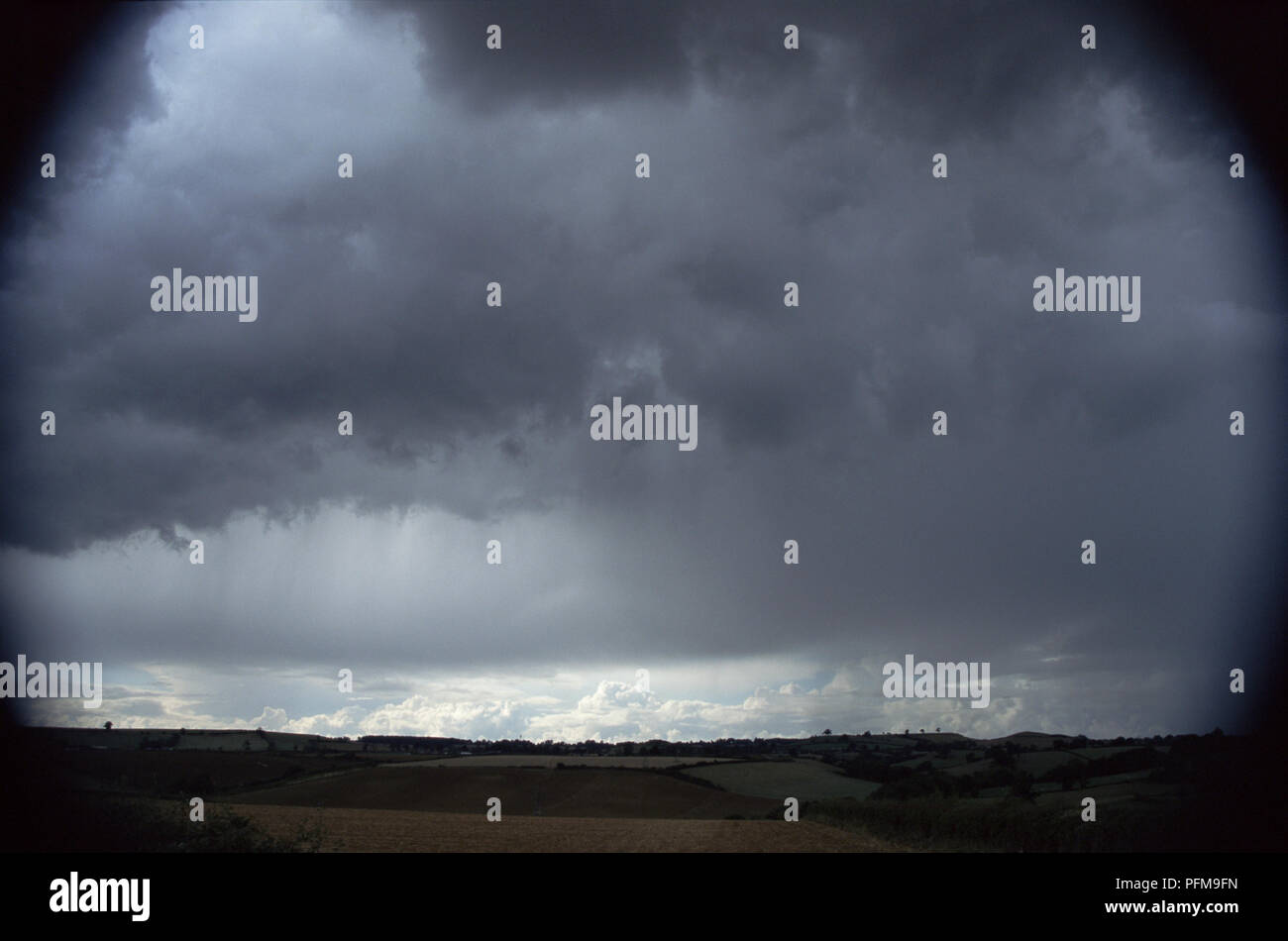 Cumulonimbuswolken bilden Squall line mit Sonne durch Patches, hellen Himmel in Distanz, Felder durch schwere Gewitter wolken unter abgedunkelten Stockfoto