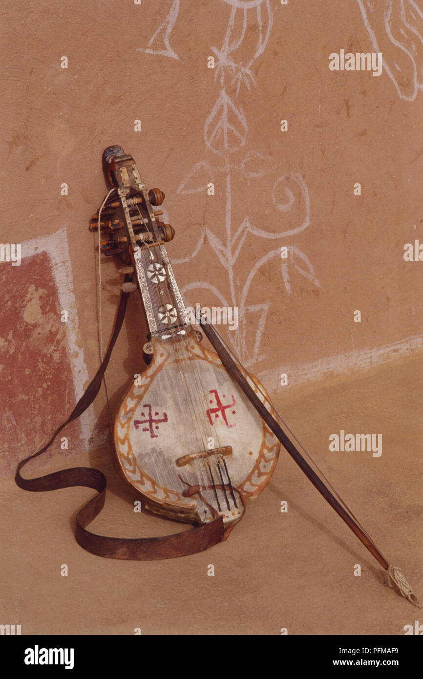 Sarangi und Bogen, traditionelle indische Saiteninstrument, lehnte sich gegen die Wand. Stockfoto