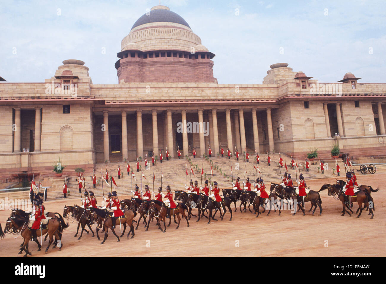 Indien, Delhi, staatliche Prunk mit rot uniformierte Männer zu Pferd, auf dem Vorplatz der Rashtrapati Bhavan, die offizielle Residenz des Präsidenten von Indien, genannt Viceroy's House in der Kolonialzeit, auf dem Kamm des Raisina Hill gelegen. Stockfoto