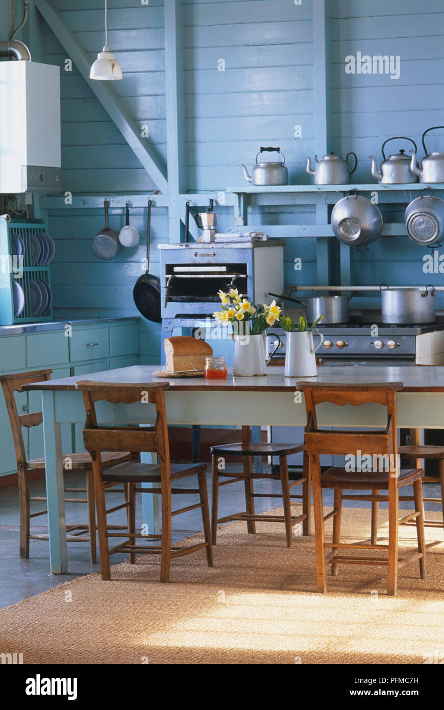 Altmodische Küche mit Edelstahl Töpfe und Pfannen, Wasserkocher, Tisch und Stühlen und einem modernen Edelstahl Gastronomie Backofen. Stockfoto