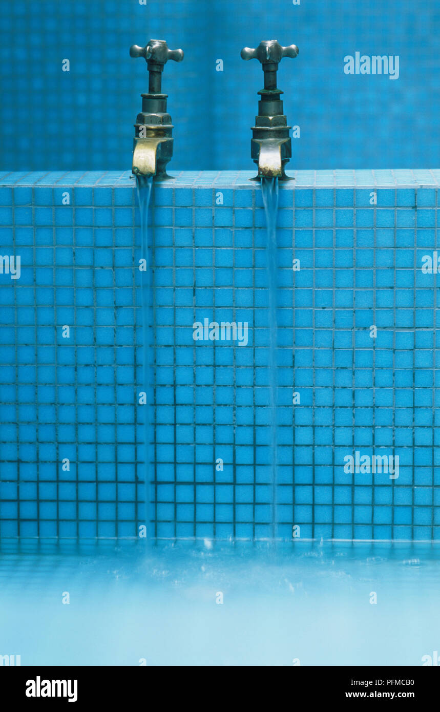 Fließendes Wasser aus der Badewanne tippt auf ein mit Mosaikfliesen ausgelegtes Bad. Stockfoto