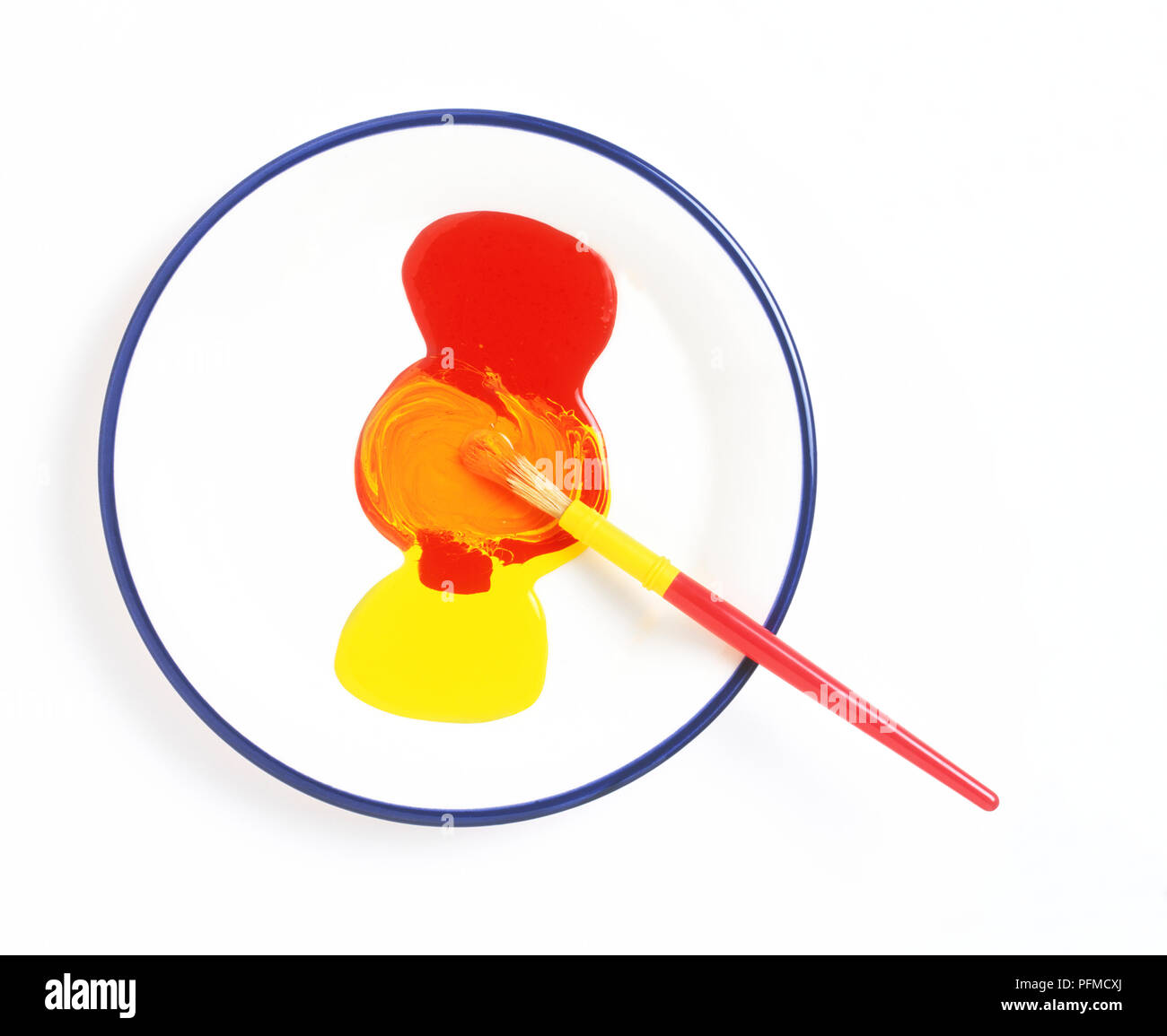 Mischen rote und gelbe Farbe auf eine Platte mit einem kleinen Pinsel, Ansicht von oben Stockfoto