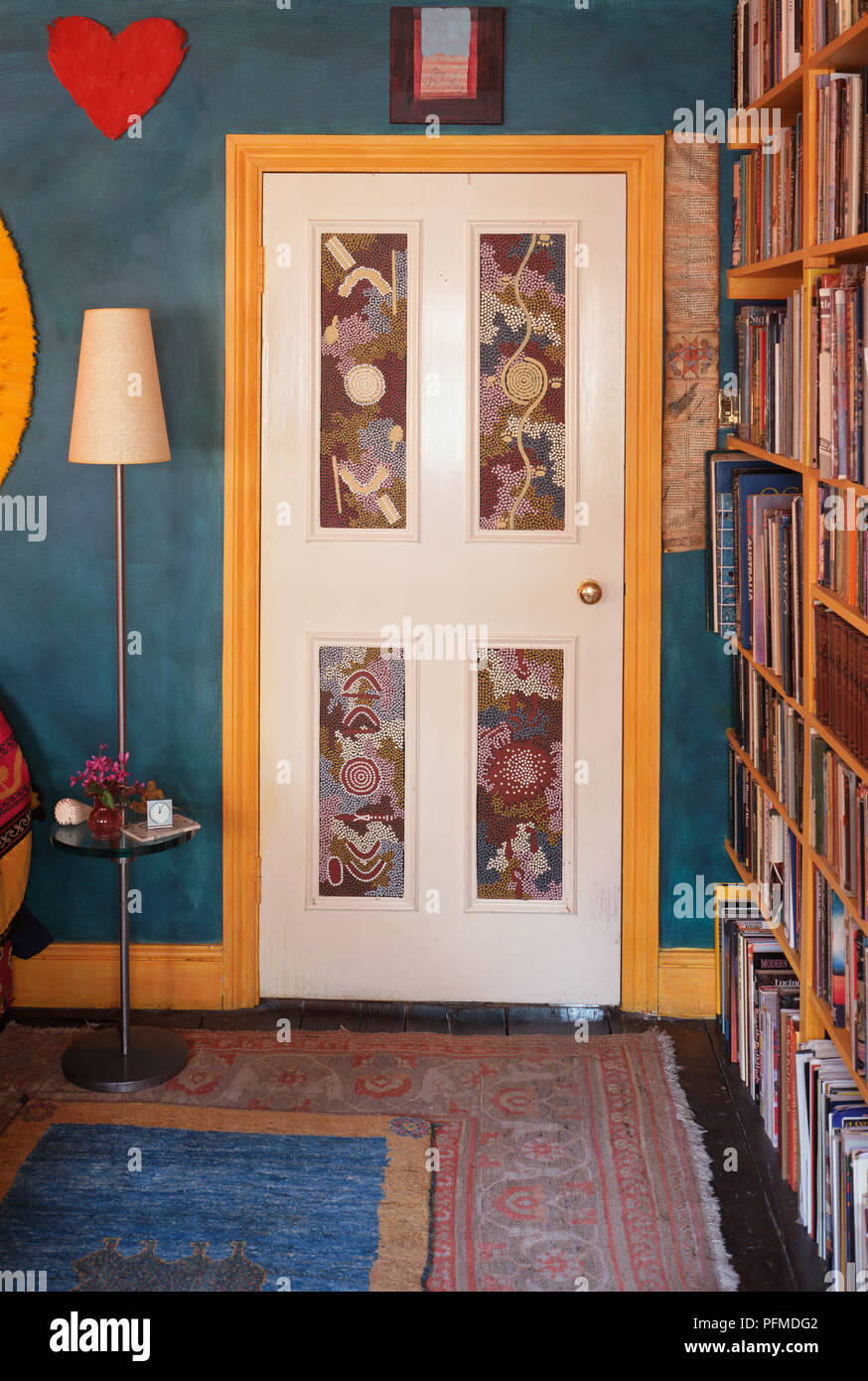 Weiße Tür, Panels mit Mustern verziert, in großen blauen Raum, hohe Leuchte neben der Tür, hohe bücherregale Futter Wand. Stockfoto