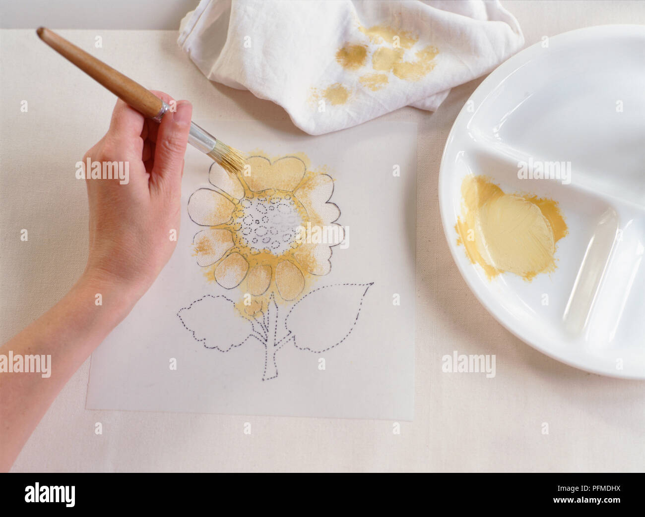 Hand blotting hellgelbe Farbe auf Blüten der Sonnenblume Schablone, Malerei weißen Stoff unten, mit hölzernen - Pinsel bearbeitet. Stockfoto
