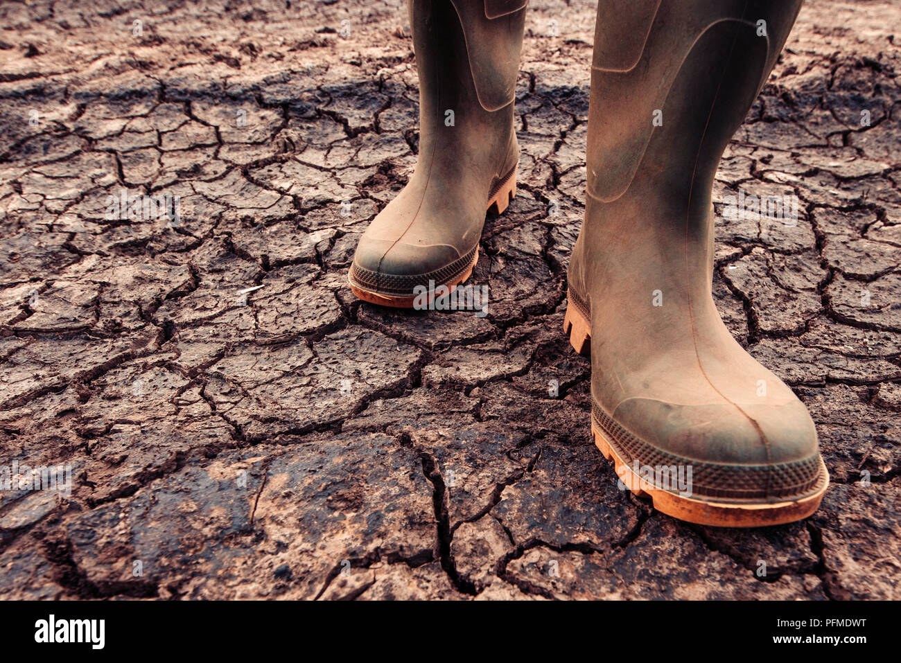 Landwirt in Gummistiefel stehen auf trockenem Boden Boden, die globale Erwärmung und den Klimawandel wirkt sich Kulturen, und Ausbeute Stockfoto