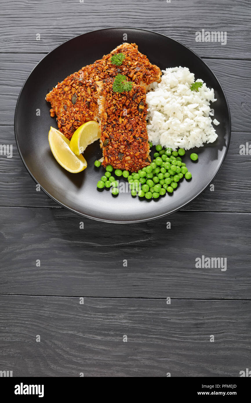 Kürbis, Sonnenblumen und Chili - Fischfilets mit Reis, Erbsen und Zitronenscheiben auf schwarze Platte verkrusteten serviert, vertikale Ansicht von oben Stockfoto