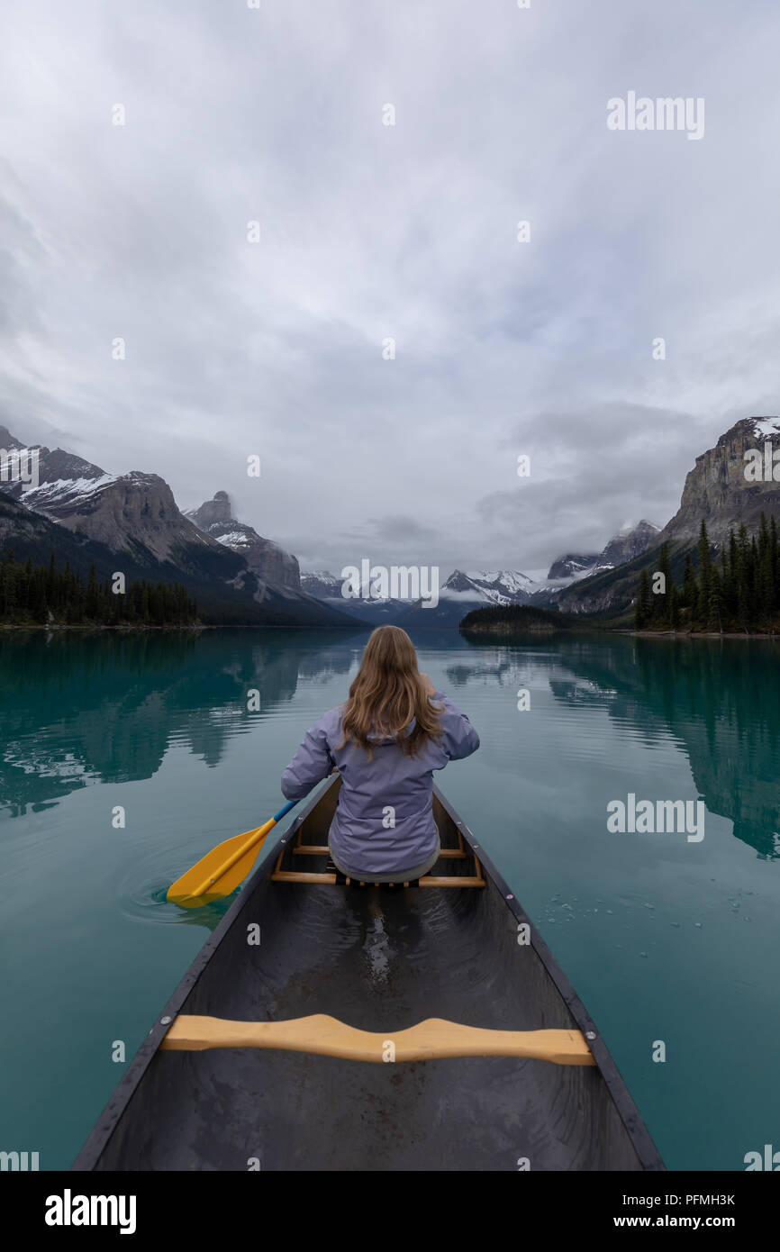 Eine weiße Frau mit einem Kanu Paddel auf Maligne Lake im Jasper Nationalpark umgeben von Bergen Stockfoto