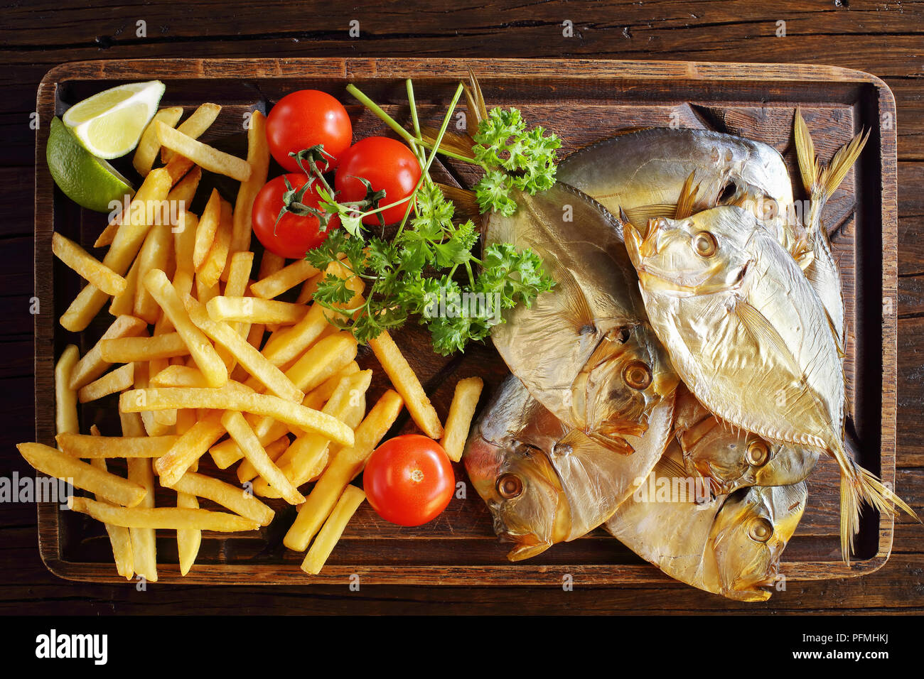 Köstlich kalt geräuchert Mond Fisch und Pommes frites auf braun Schneidbrett auf rustikalen Holztisch serviert, Ansicht von oben, close-up Stockfoto