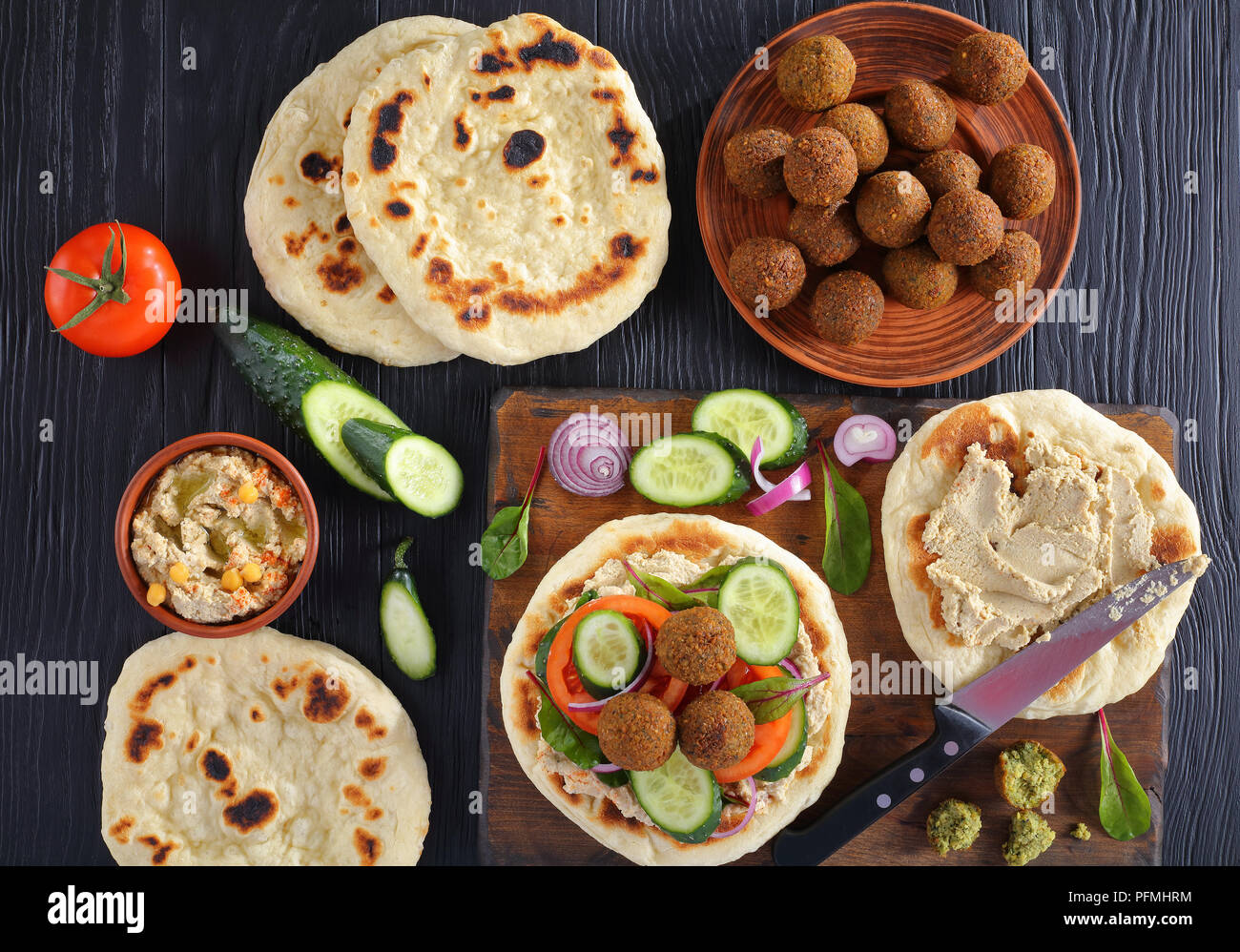 Falafels auf pan fried Fladenbrot mit würziger Hummus, Tomaten und Gurkenscheiben. Zutaten auf Hintergrund, horizontale Ansicht von oben Stockfoto