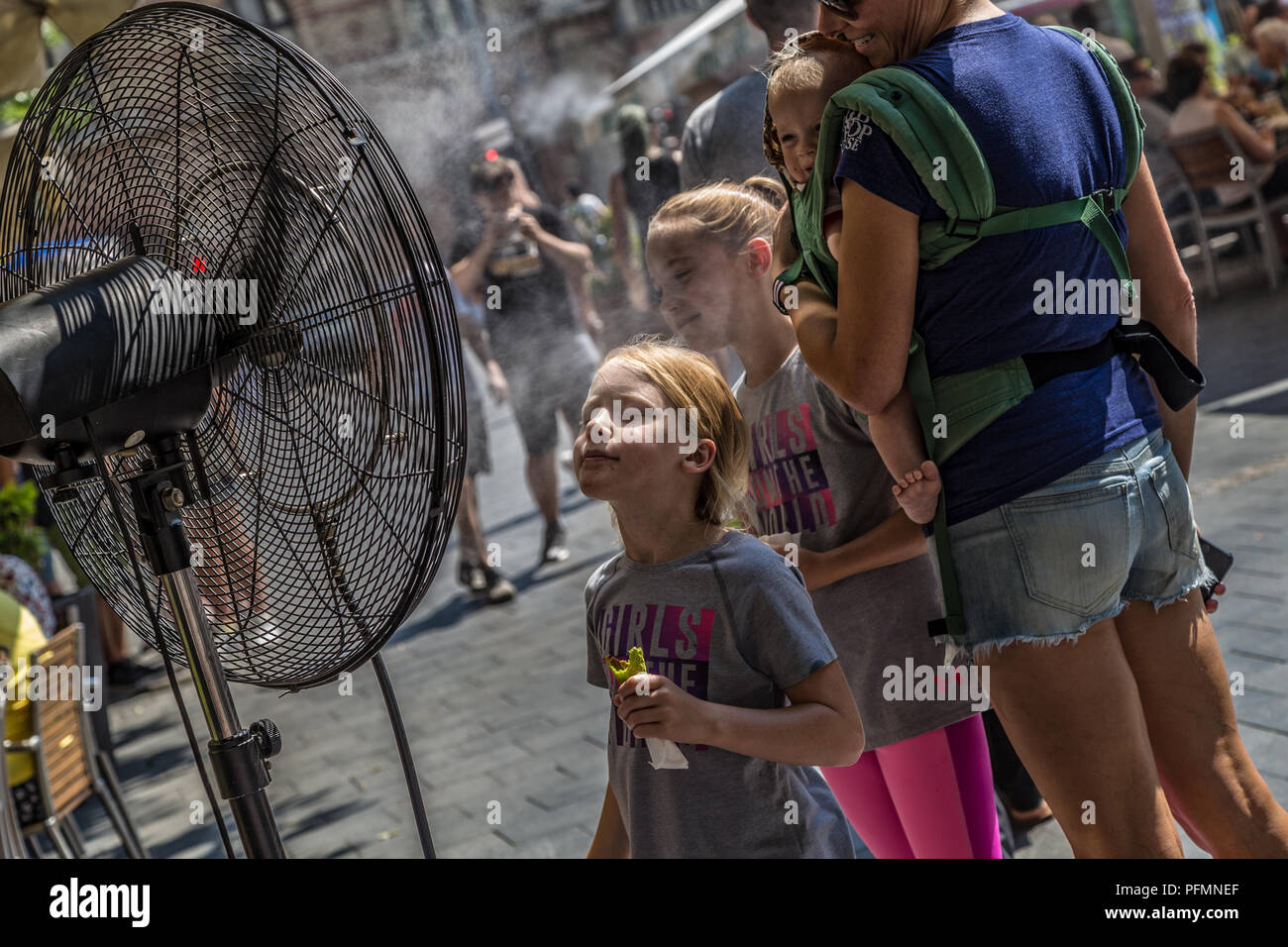 BUDAPEST, Ungarn - August 09,2018: Menschen Hitzewelle dieses Sommers vor dem Wasser spritzen Lüfter auf der Straße in der Innenstadt zu verringern. Stockfoto