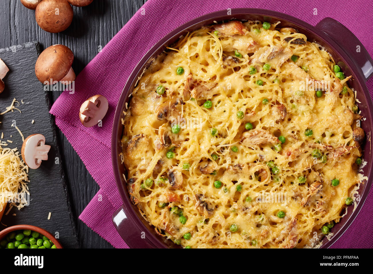 Tetrazzini - Spaghetti, Geflügelfleisch, geriebener Käse, grüne Erbsen, Champignons Auflauf in einer Auflaufform mit Zutaten im Hintergrund, amerikanische Küche Stockfoto