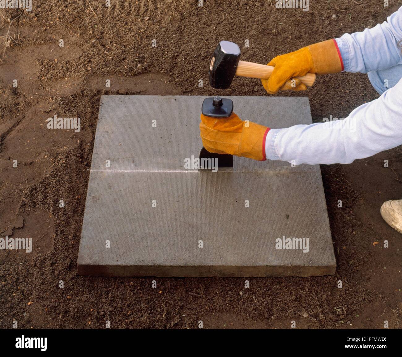 Schneiden einen pflasterstein Platte, mit einem Kropf und Fäustel entlang einer Linie gezählt Stockfoto