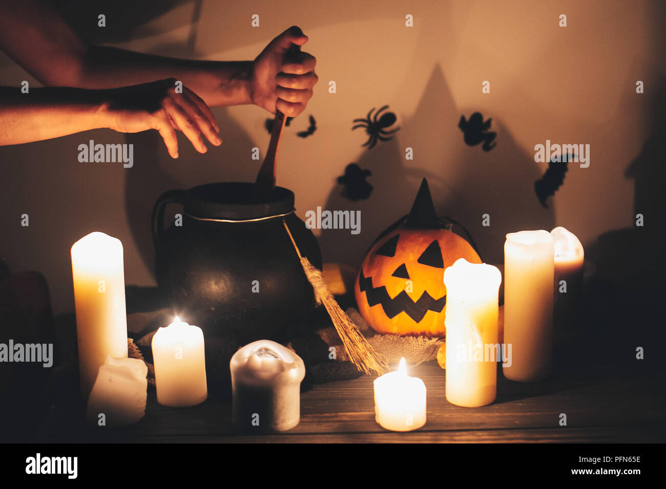 Hexe hand kochen Trank für Zauber, mit jack o lantern Kürbis mit Kerzen, Besen und Fledermäuse, Geister im Hintergrund im Dunkel gruseligen Zimmer. Happy Hallowe Stockfoto