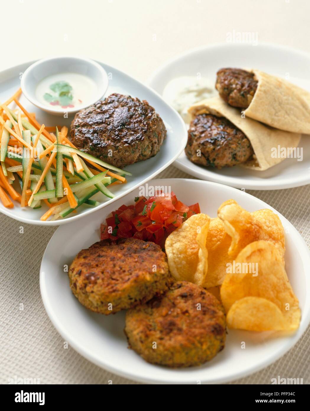 Thai Lamm Burger serviert mit Gurke, Karotte Sticks, Tzatziki, und Pitta Brot, veggie Burger mit Tomate Salsa auf weiße Platten Stockfoto