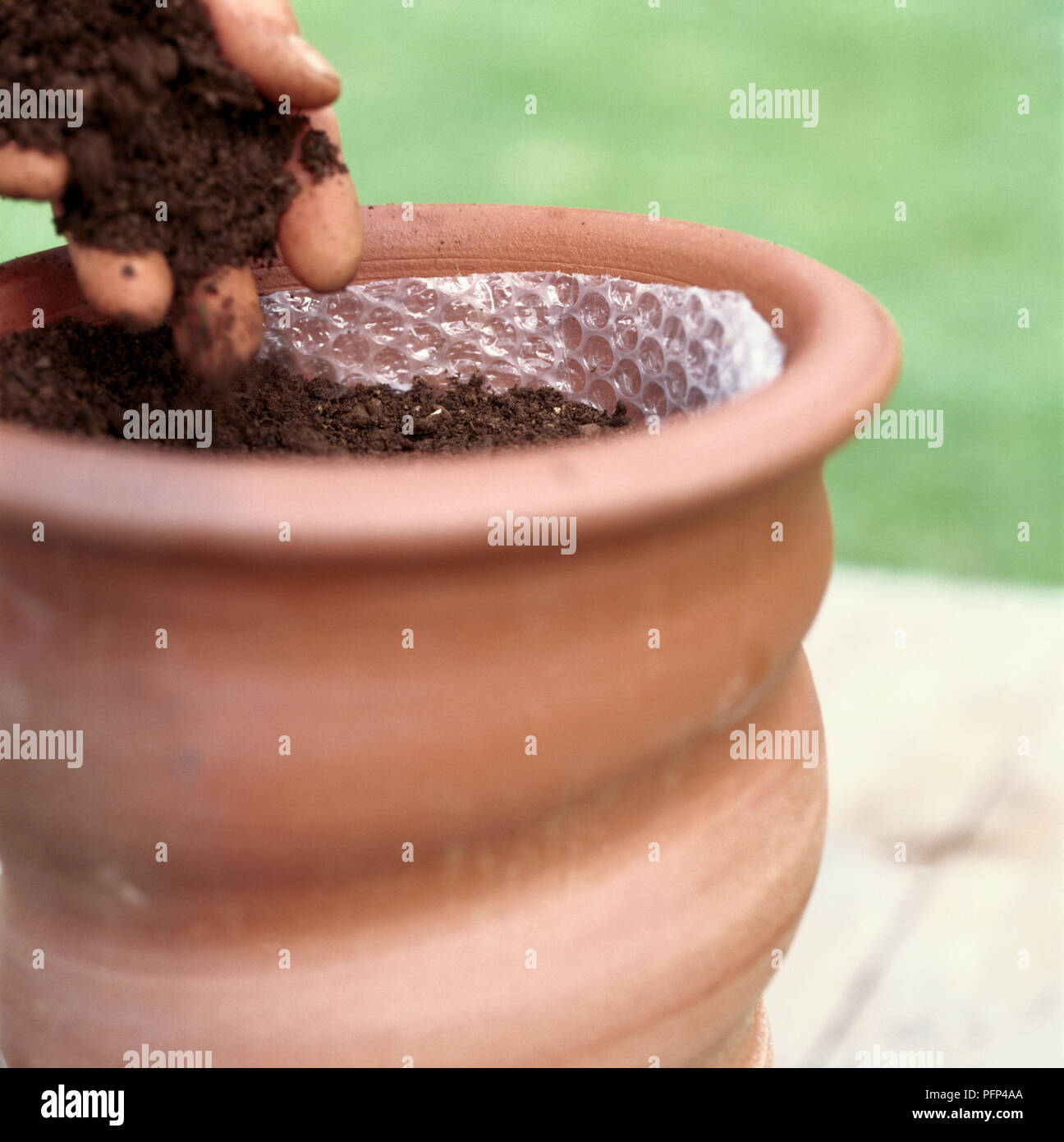 Terracotta Blumentopf mit Luftpolsterfolie ausgekleidet und mit Kompost gefüllt, close-up Stockfoto