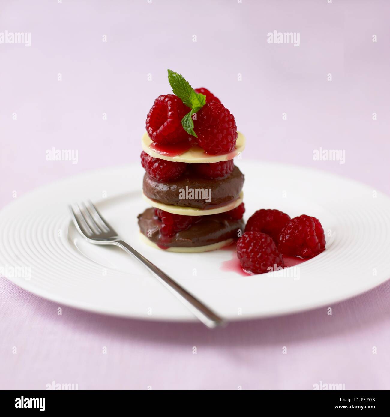 Milch Schokolade und Himbeere Türme serviert auf weiße Platte mit Dessert Löffel Stockfoto