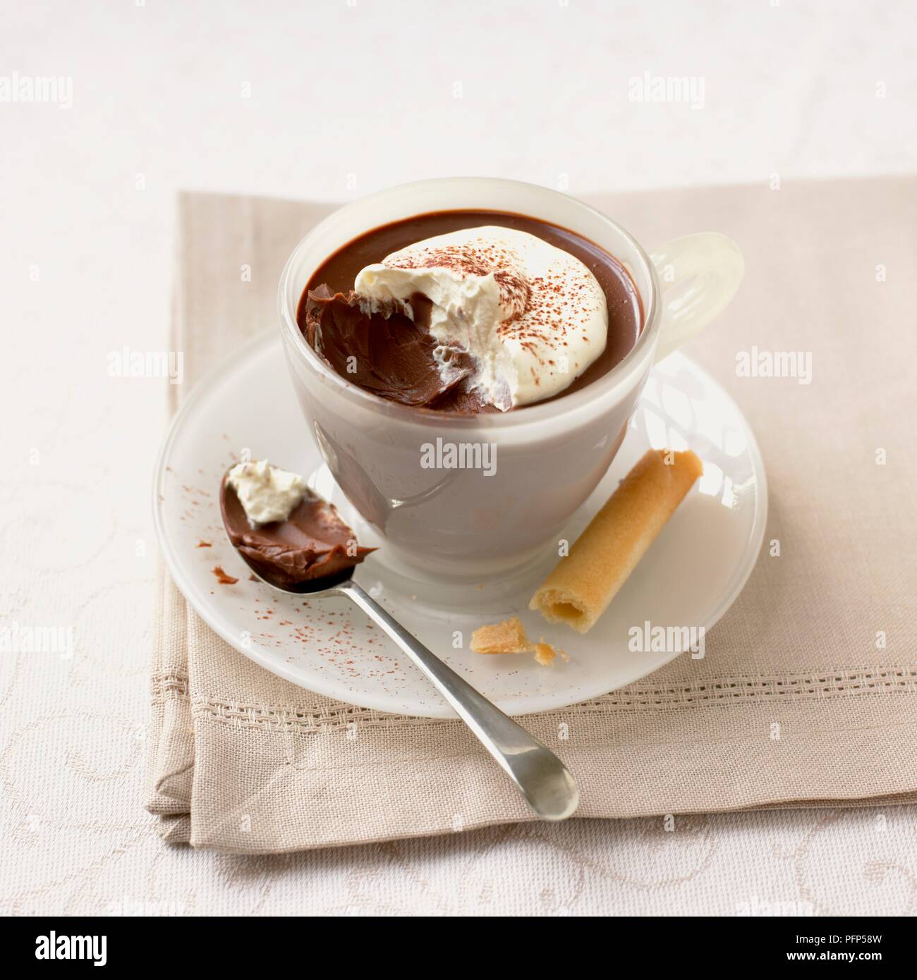 Schokolade Cappuccino pudding serviert in Schale, mit Biskuit und Löffel, auf eine Serviette Stockfoto