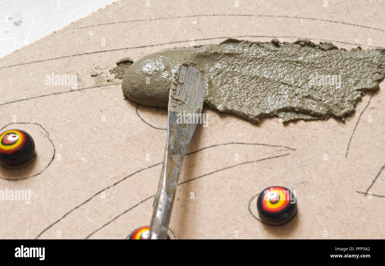 Mit einem Spachtel fliesen Kleber auf die Platine zu verbreiten, (smalti) kleine Stücke von Glas tessera bereits auf geklebt, close-up Stockfoto