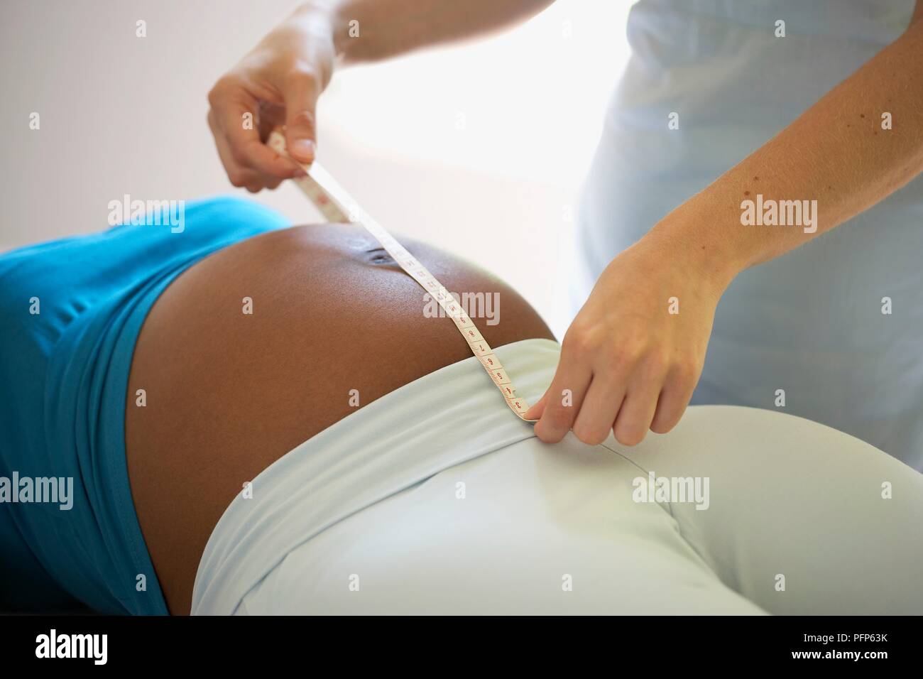 Krankenschwester Messung der Höhe des Augenhintergrundes (oben in der Gebärmutter) auf dem Bauch einer schwangeren Frau Stockfoto