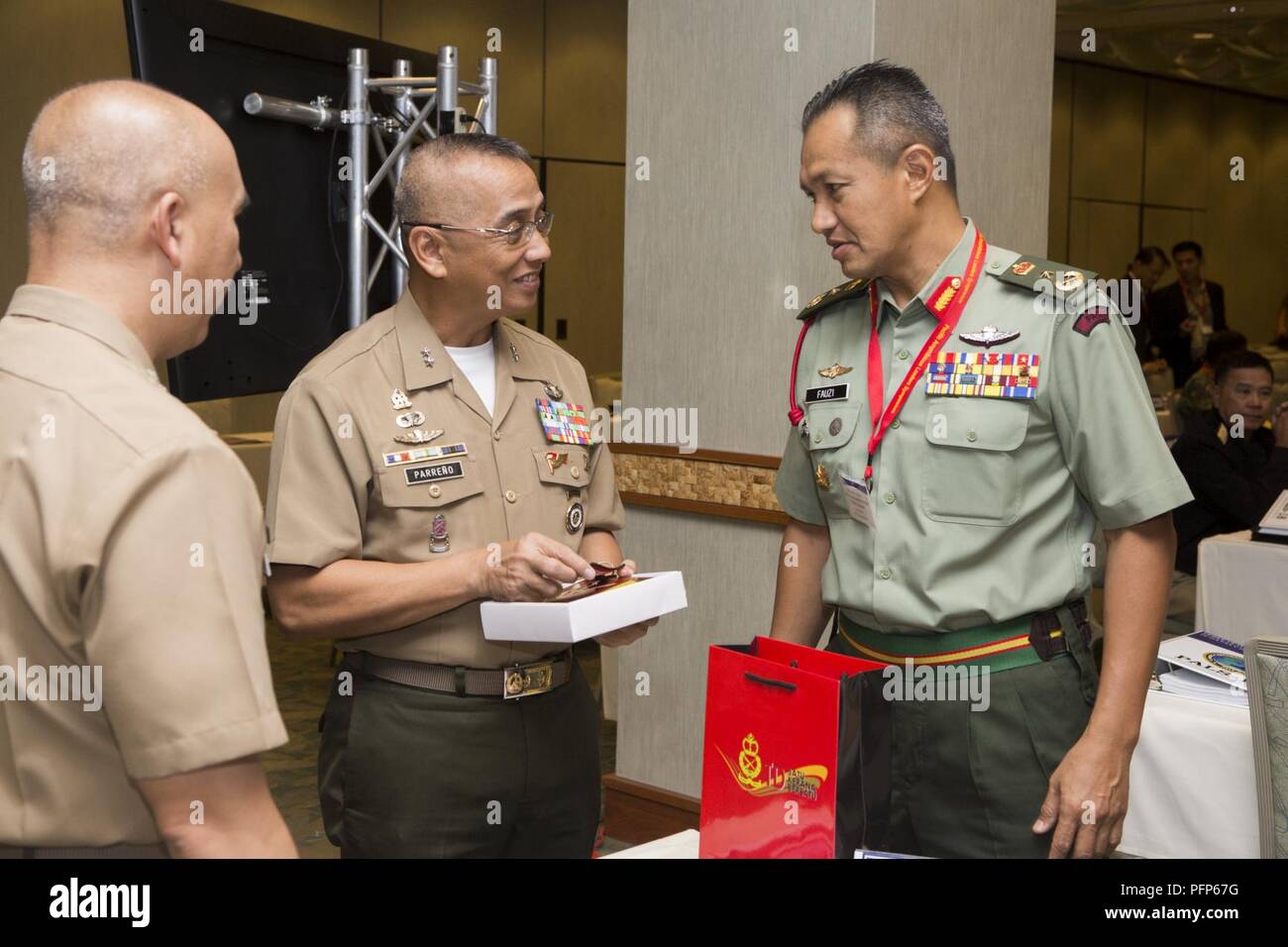 Philippinische Marine Corps Generalmajor Alvin A. Parreno, Mitte, Kommandant, philippinische Marine Corps, erhält ein Geschenk von malaysischen Brig. Gen. Tengku Muhammad Fauzi Tengku Ibrahim, rechts, Commander, 10 Brigade, während der Pazifik amphibischen Führer Symposium (PALS) 2018 in Honolulu, Hawaii, 24. Mai 2018. PALS bringt Führungskräfte der Alliierten und Partner Militärs mit großes Interesse an der Sicherheit und Stabilität des Indo-pazifischen Region wichtige Aspekte der maritimen/amphibischen Operationen zu diskutieren, der Entwicklung der Fähigkeiten, Krisenmanagement und Interoperabilität. Stockfoto