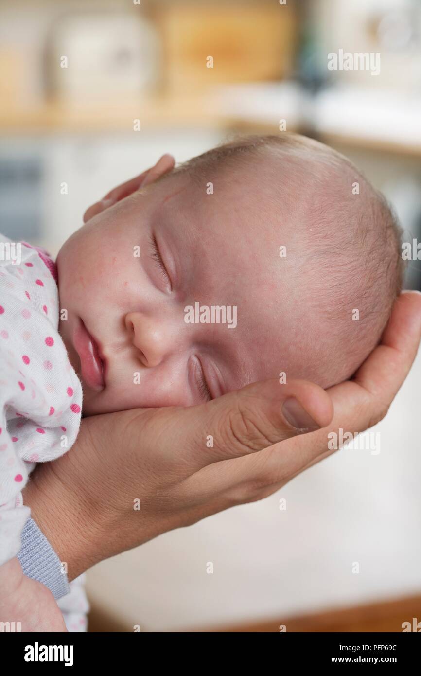 Baby Girl's Kopf in der Hand eines Mannes, close-up Stockfoto