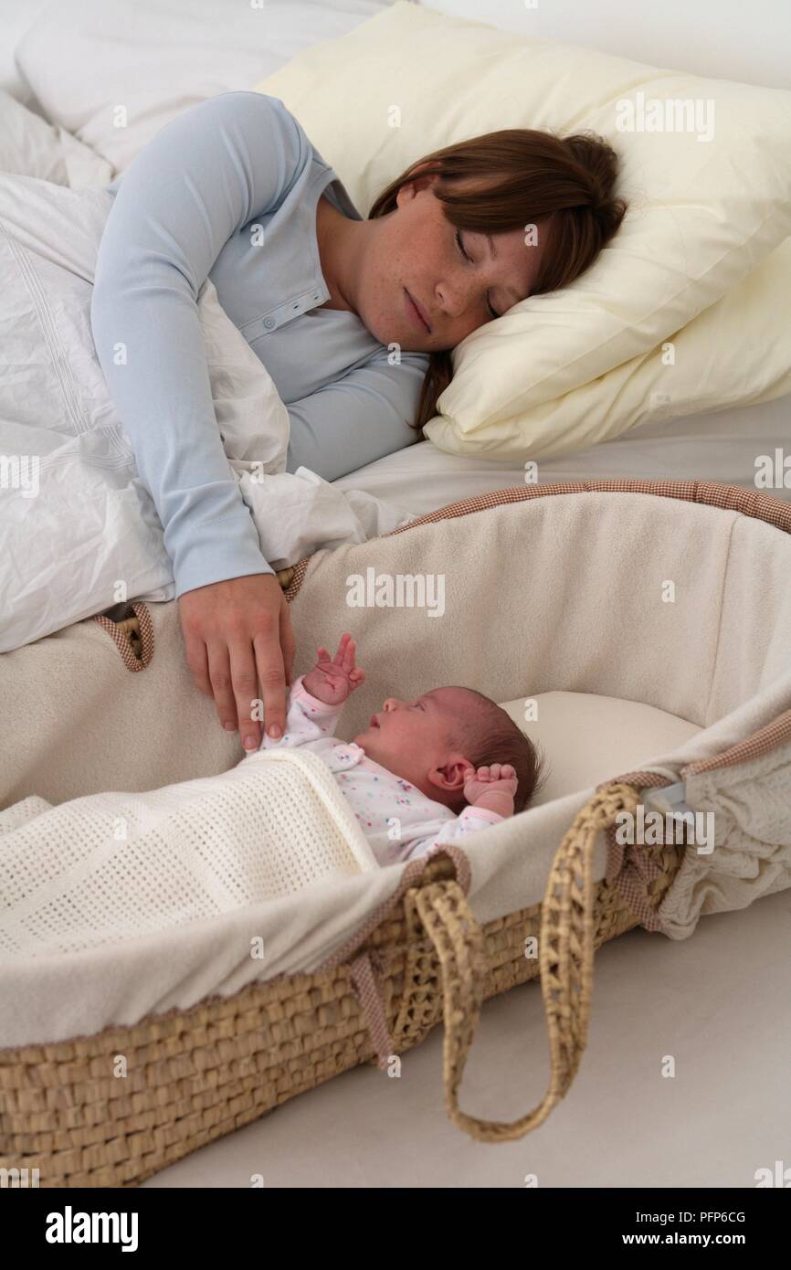 Frau liegen im Bett neben Moses Korb mit Baby Mädchen innen Stockfoto