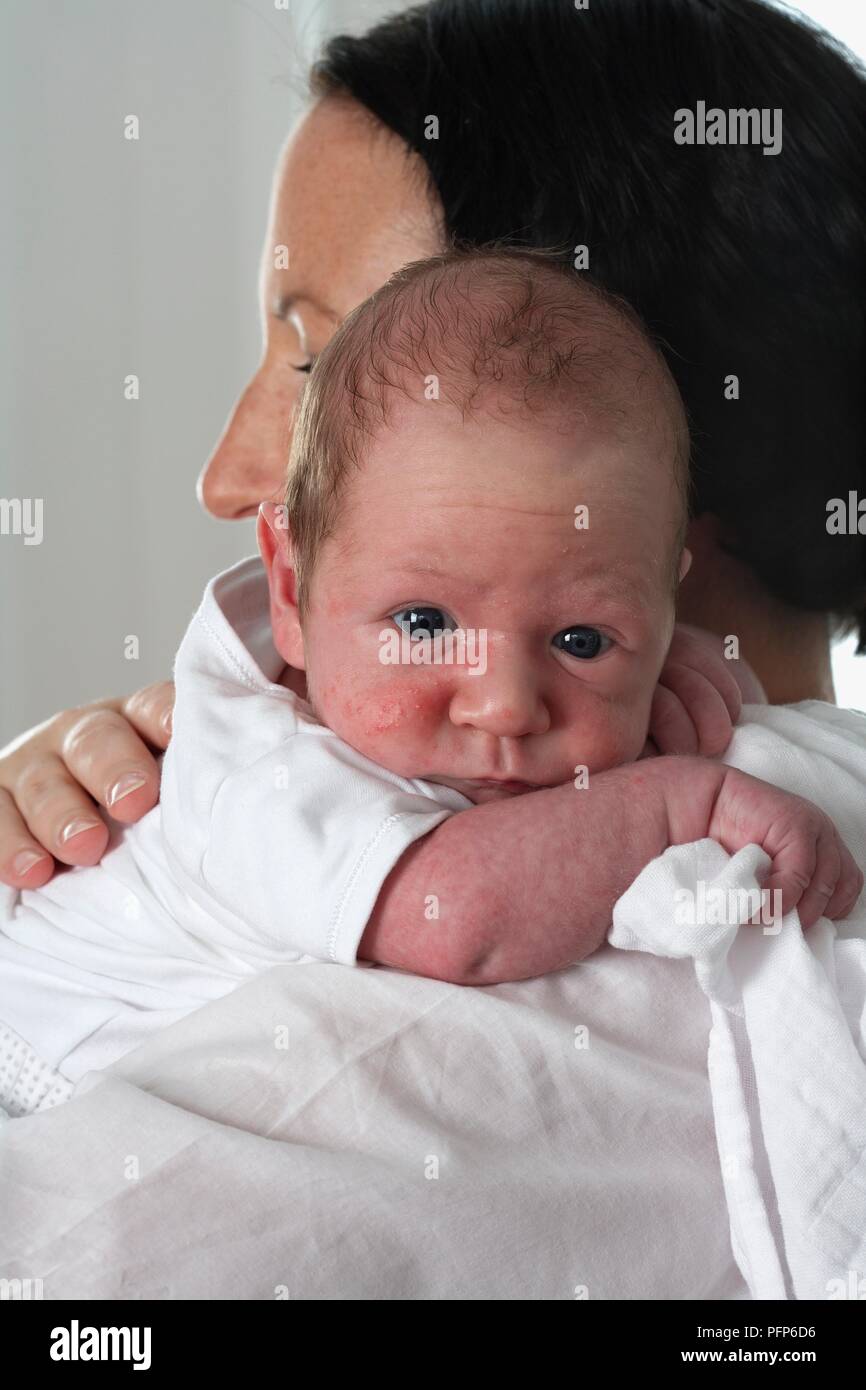 Baby Boy beugte sich über die Schulter einer Frau mit einem Stück der Musselin in seiner Hand, Nahaufnahme Stockfoto
