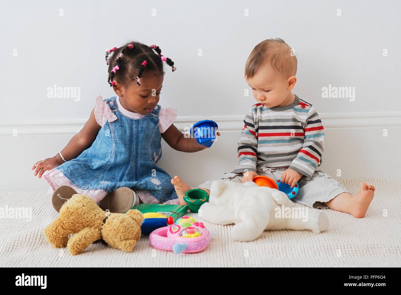 13 Monate altes Baby Mädchen und 10 Monate altem Baby Junge sitzt auf dem  Boden mit Spielzeug spielen Stockfotografie - Alamy