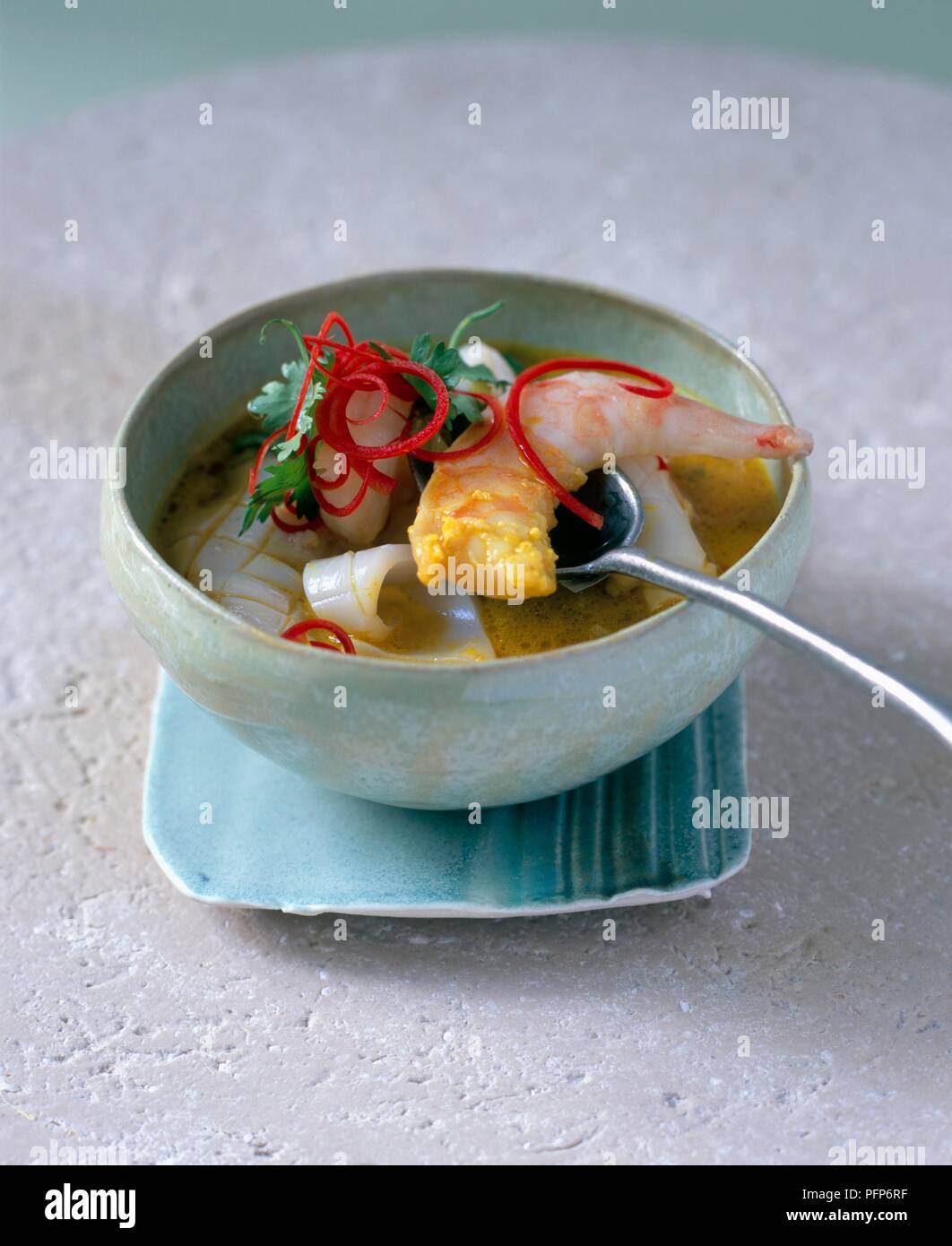 Moily Haldi, Sri Lankan coconut und Kurkuma Fischsuppe mit Garnelen, Tintenfisch und weißem Fleisch Fisch, garniert mit roter Chili und Koriander Stockfoto