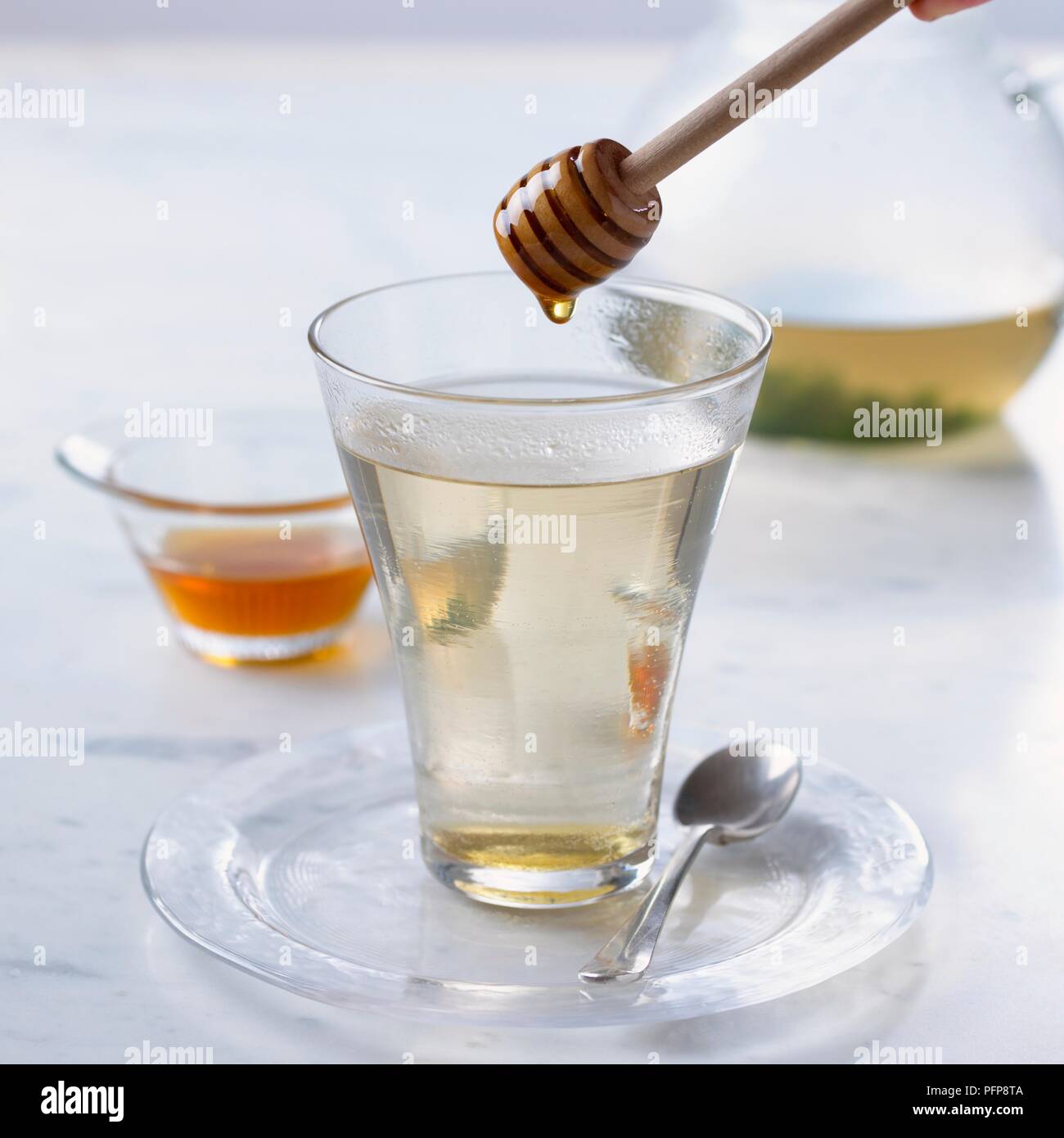 Hinzufügen von Honig zu Glas Kräutertee, Pendelarm, Schließen Stockfoto