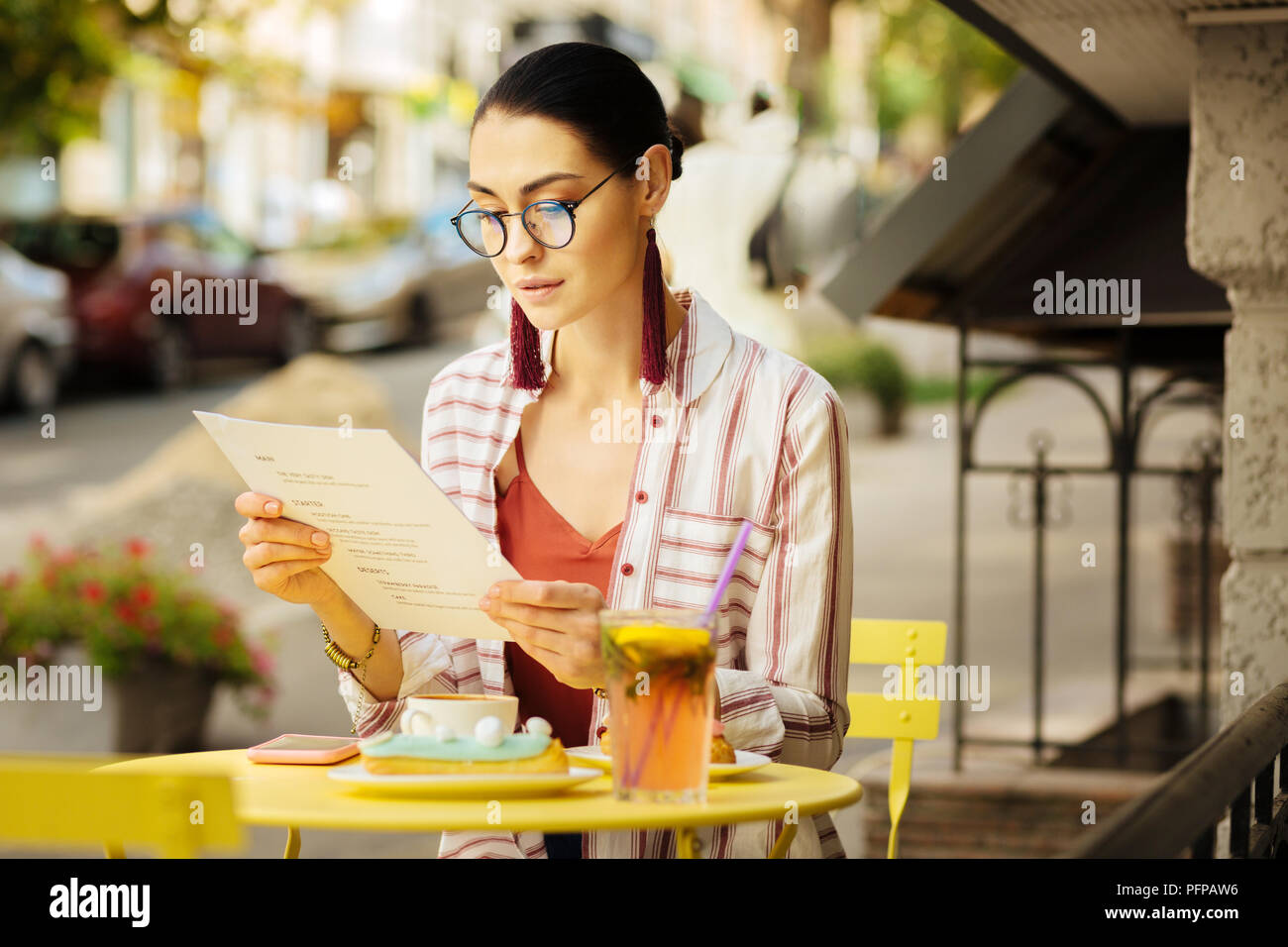Ruhe Frau suchen, um durch das Menü, während er in einem Cafe Stockfoto