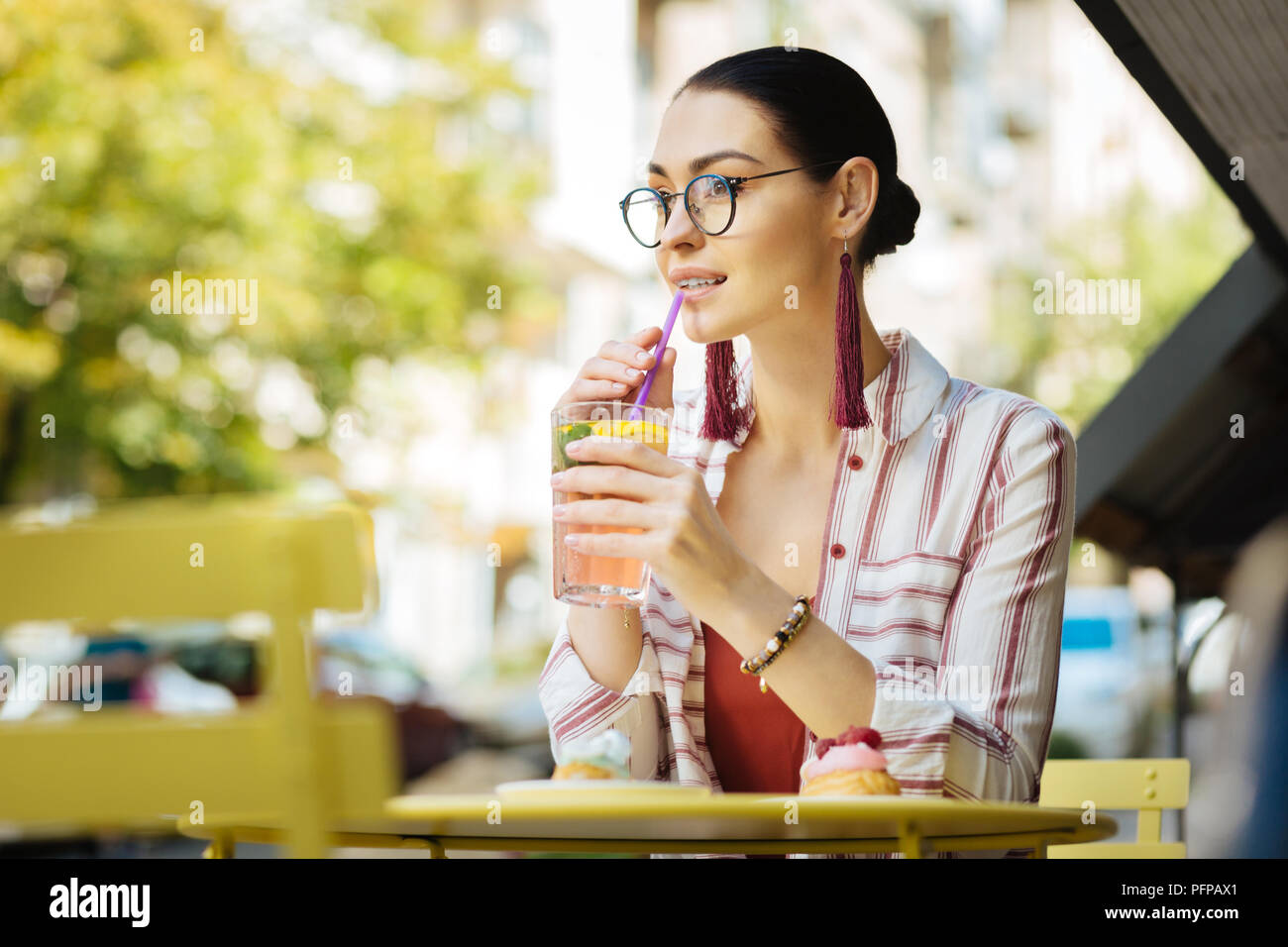 Junge Frau trinkt kalte Limonade und Berühren eines sipping Stroh Stockfoto