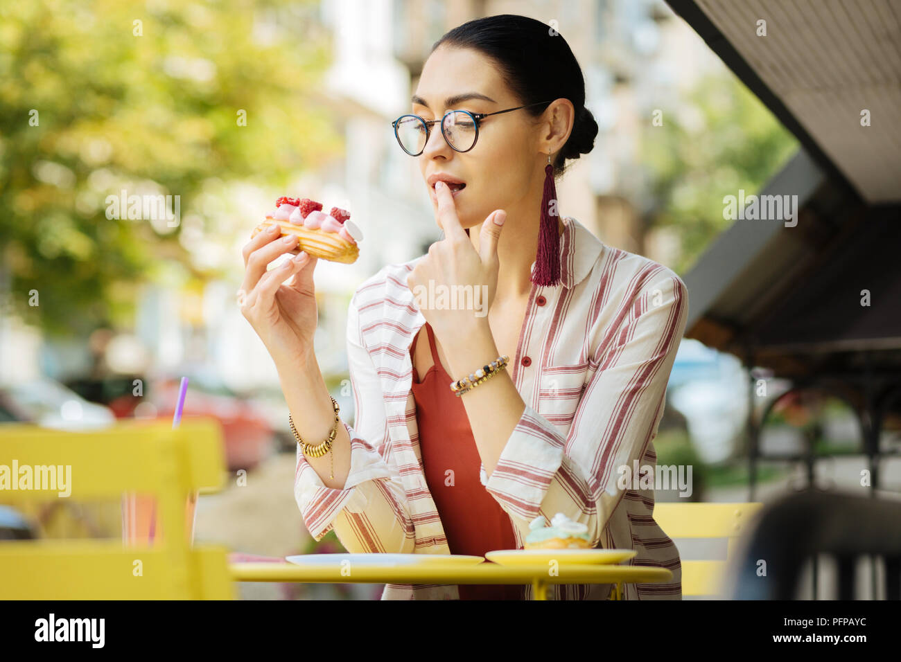Emotionale Frau lecken einen Finger beim Essen leckeres Essen Stockfoto
