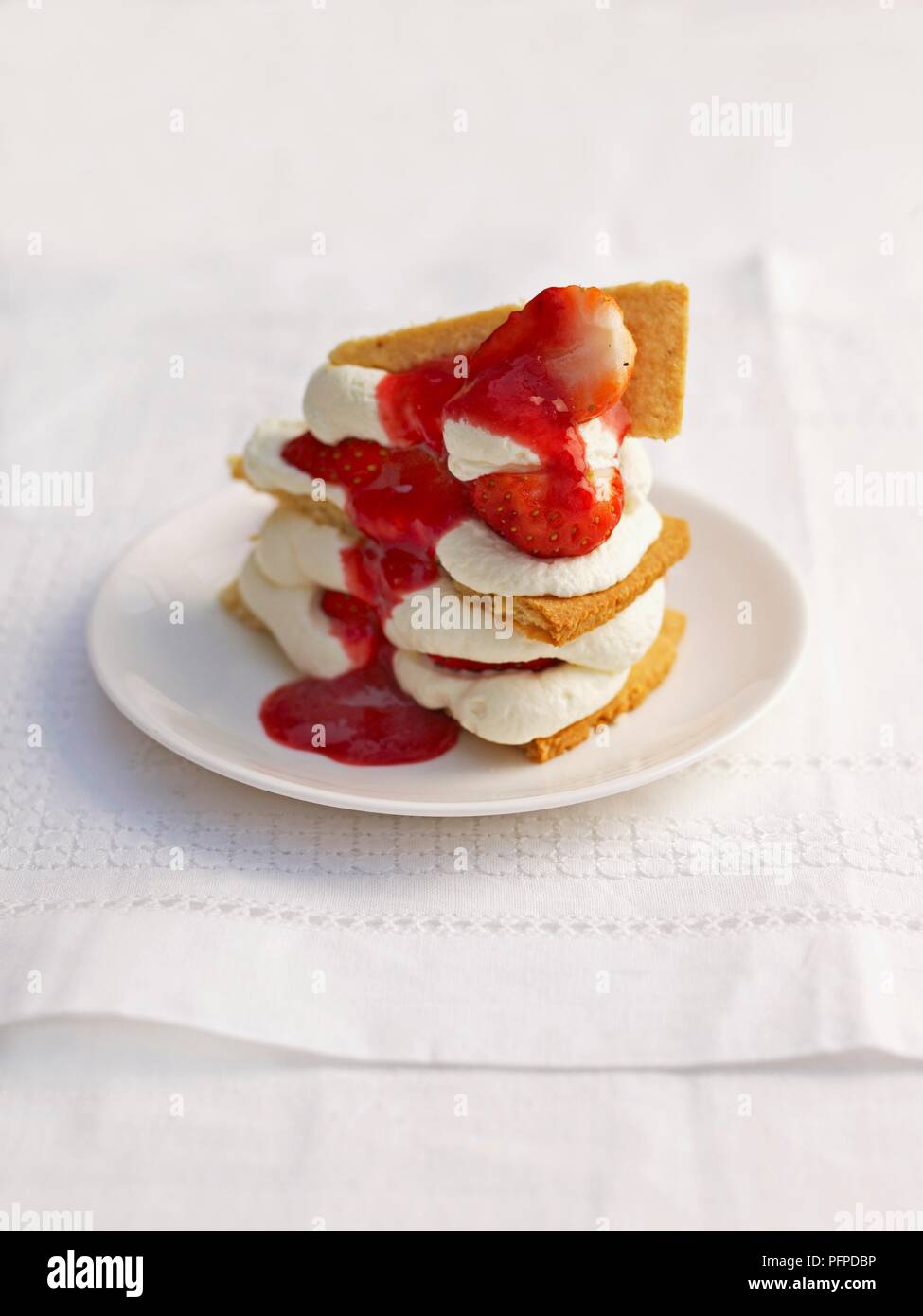 Close-up von Haselnuss und Sahne Torte mit erdbeersauce vor weißem Hintergrund Stockfoto