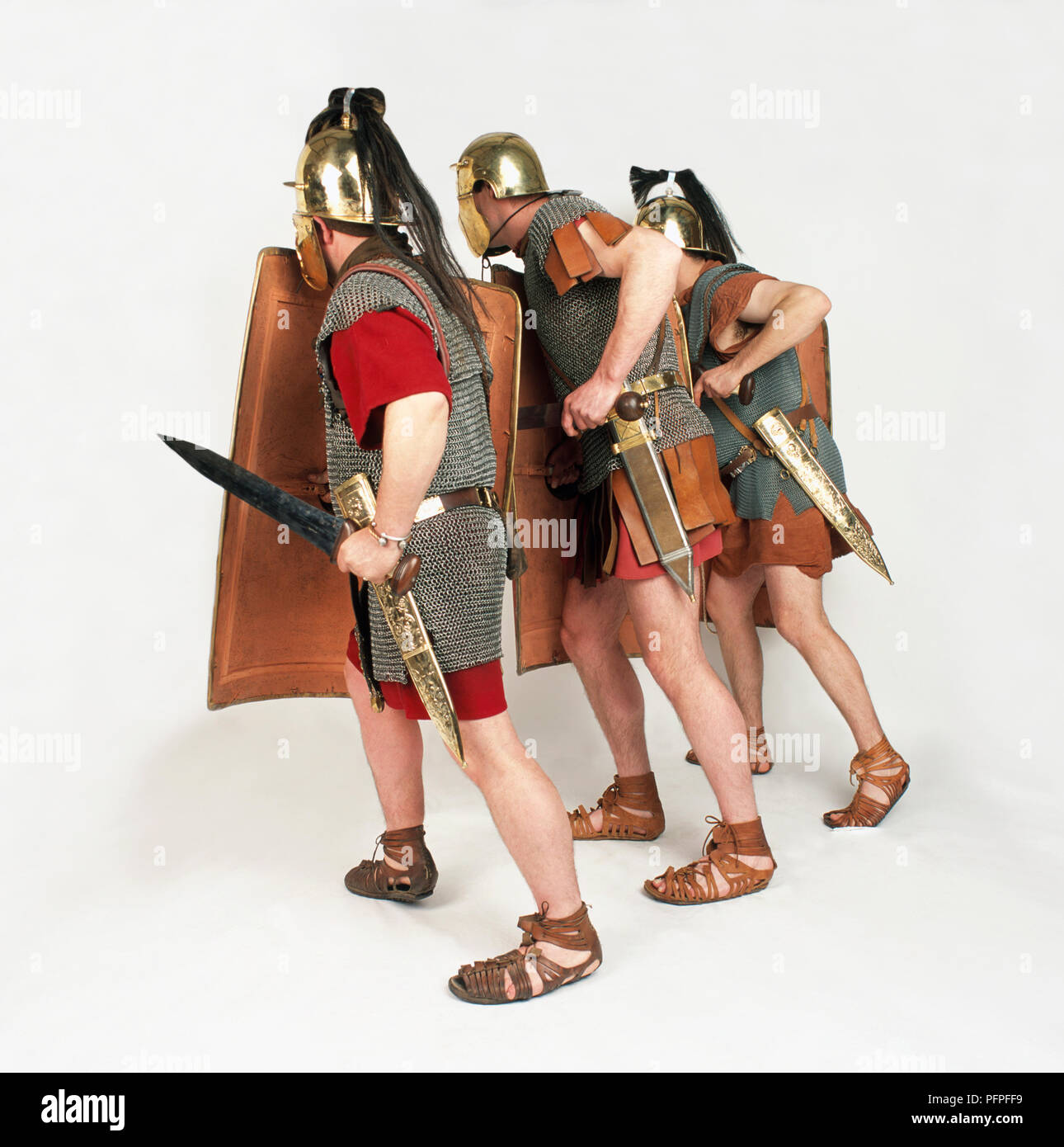 Drei römische Soldaten halten Schilde und Schwerter, drei Viertel Rückansicht Stockfoto