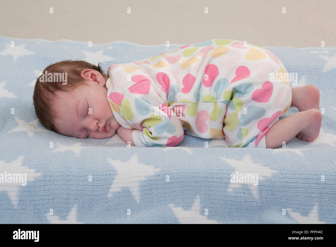 Baby Mädchen schlafend zusammengerollt auf ihren vorderen auf weichen Oberfläche Stockfoto