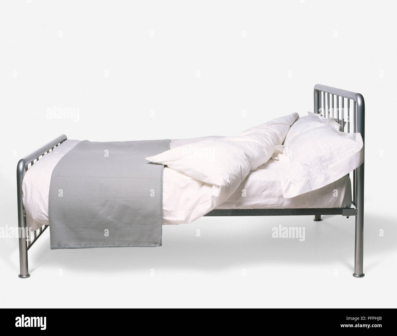 Bett mit Retro revival Metallrahmen, weiße Laken, Kissen, Bettdecke und gefaltet grau Bett Abdeckung Stockfoto