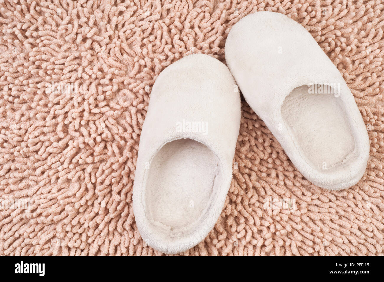 Paar weiche weiße Kinder Hausschuhe auf beige Shag flauschige Teppiche, Ansicht von oben Stockfoto