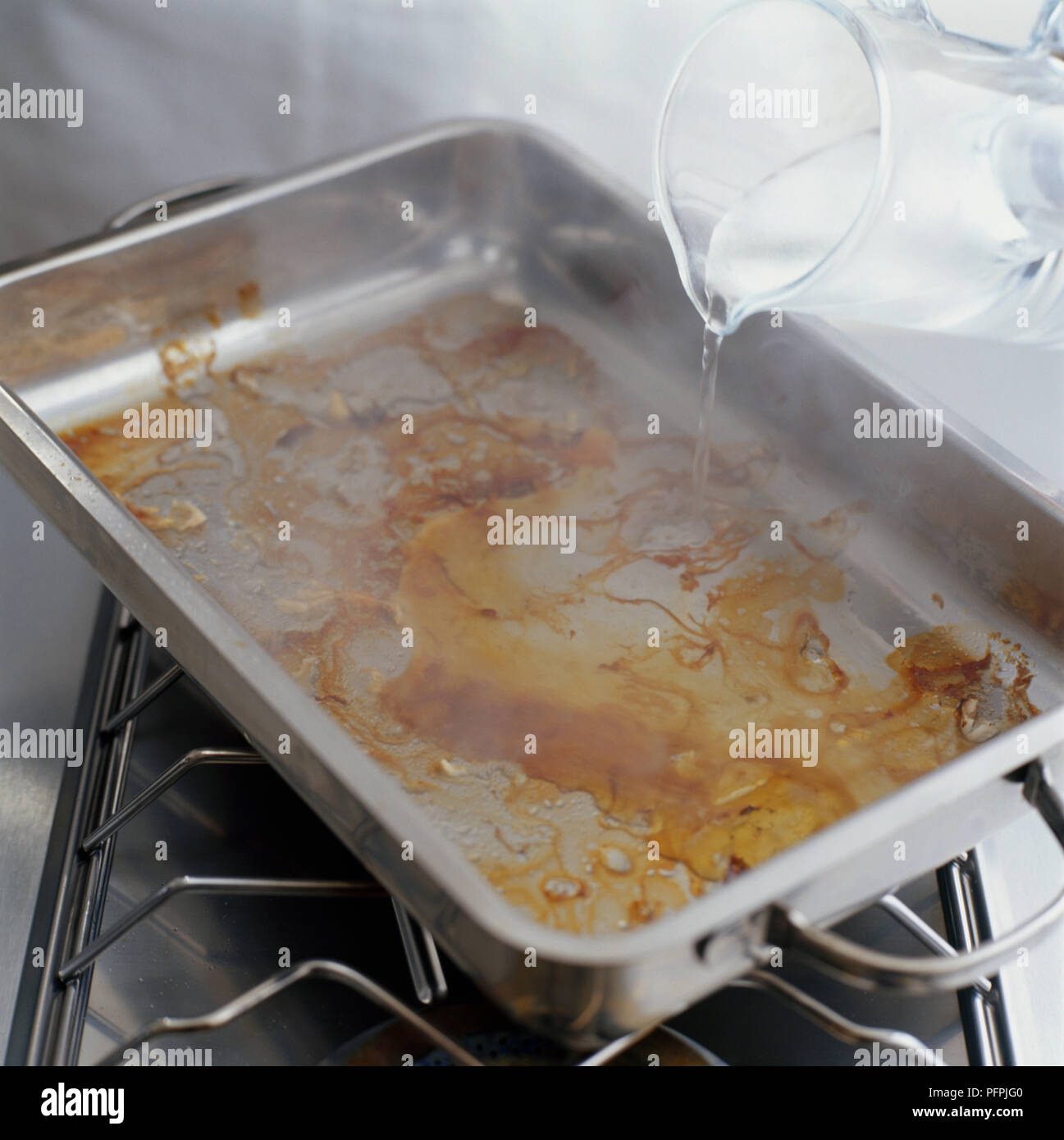 Das Hinzufügen von Wasser zu einem Bräter Stockfoto