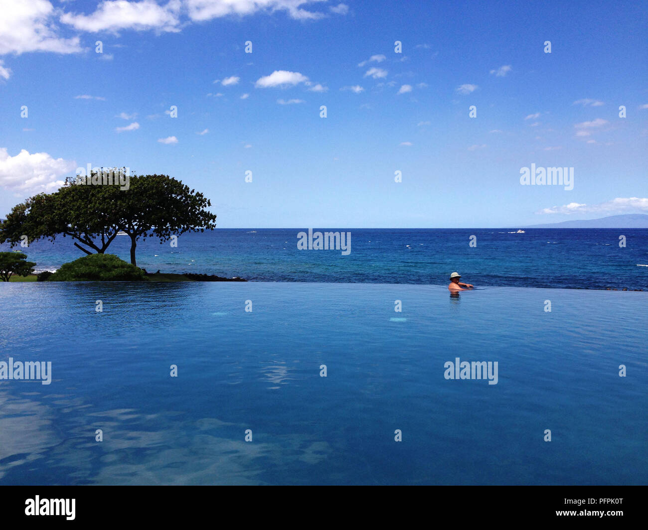 Ein Mann der Entspannung im Pool und genießen Sie die herrliche Aussicht auf das Meer. Ein Urlaub Konzept Stockfoto