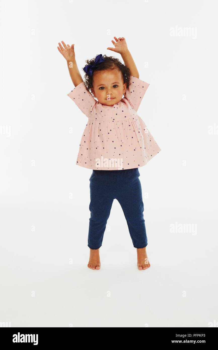 Kleine Mädchen in rosa Anfang spielen mit den Armen in der Luft (Modell Alter - 19 Monate) Stockfoto