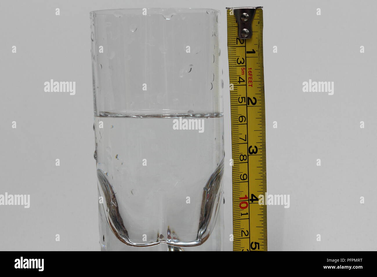 Halb voll oder halb leer. Glas Wasser und Messung Klebeband nebeneinander Stockfoto