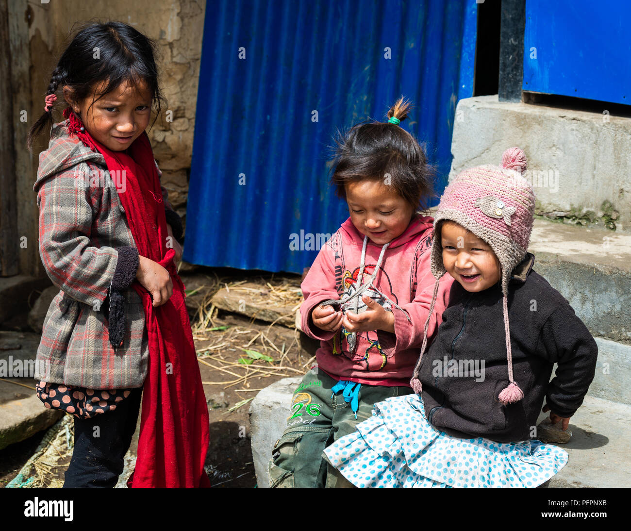 GHALEGAUN, Nepal - ca. Mai 2018: Drei junge nepalesische Mädchen außerhalb ihres Hauses zu spielen. Stockfoto