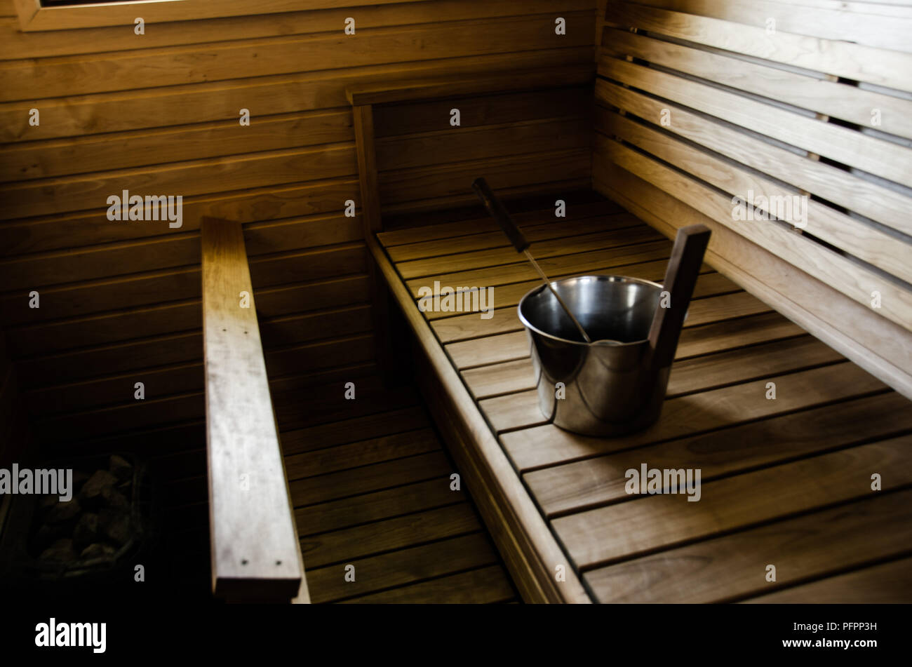 Sauna mit einem Eimer Wasser auf die heißen Steine werfen. Stockfoto