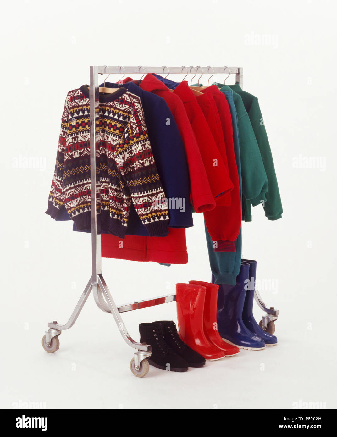 Kleiderstange mit verschiedenen Jacken und Mäntel mit Schuhen unter gefüttert Stockfoto